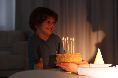 Doğum günü kutlaması. Anne, oğlunun yanında yanan mumlarla lezzetli bir pasta tutuyor.