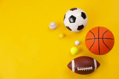 Sarı arka planda bir sürü farklı spor topu var. Metin için boşluk