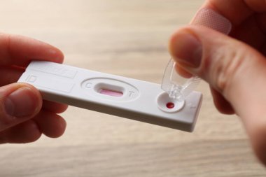Tek kullanımlık test kasetinin üzerine tampon çözeltisi atan kadın masadaki, kapat