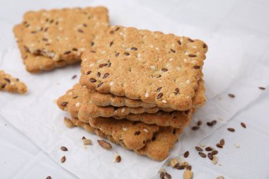 Keten ve susam tohumlu mısır gevreği yığını beyaz döşemeli masa, yakın plan.