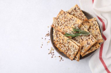 Mısır gevreği krakerleri, keten, ayçiçeği, susam tohumları ve biberiye beyaz masada, üst tarafta. Metin için boşluk