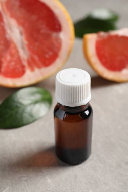 Şişedeki greyfurt yağı gri desenli masada, yakın plan.