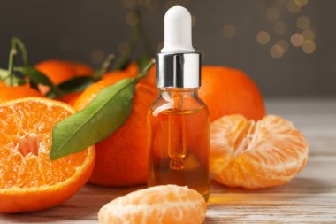 Bir şişe mandalina yağı ve beyaz ahşap masada taze meyveler, yakın plan.