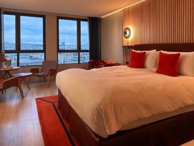 Büyük yataklı, lambalı ve masalı şık bir otel odası.