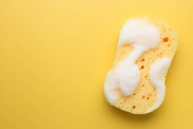 Sarı arka planda köpüklü sünger, üst manzara. Metin için boşluk