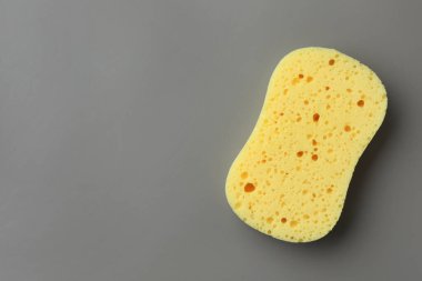 Gri arka planda yeni sarı sünger, üst manzara. Metin için boşluk