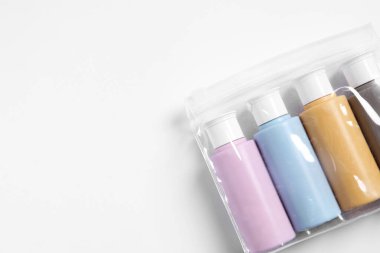 Beyaz arka planda plastik poşet içinde kozmetik seyahat kiti, üst manzara. Metin için boşluk