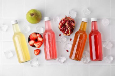 Cam şişelerde lezzetli kombu çayı, beyaz masada taze meyve ve buz, düz uzanmış