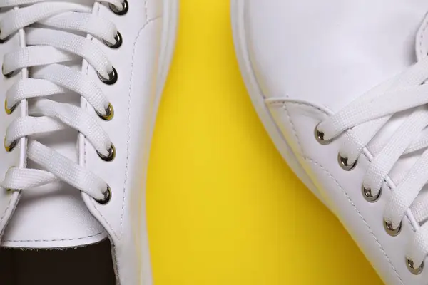 黄色の背景にスタイリッシュな白いスニーカーのペア トップビュー — ストック写真