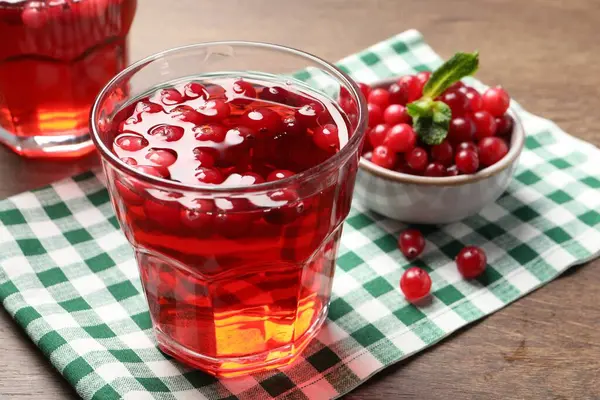 Tasty cranberry juice in glass and fresh berries on wooden table, closeup