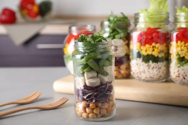 Glass jar with healthy meal on light grey table