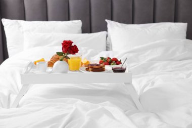 Beyaz tepsi ve yatakta lezzetli kahvaltı.