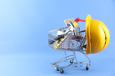 İnşaat aletleri ve arka planda kalın şapkalı küçük bir alışveriş arabası.