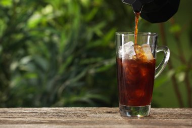 Dışarıdaki ahşap masada buzun üzerine kahve dökmek. Metin için boşluk