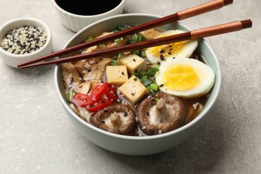 Gri masada servis edilen lezzetli ramen, yakın plan. Erişte çorbası.