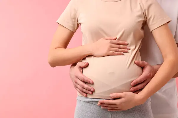 妊娠中の妻の腹をピンクの背景に触れた男 クローズアップ テキスト用スペース — ストック写真