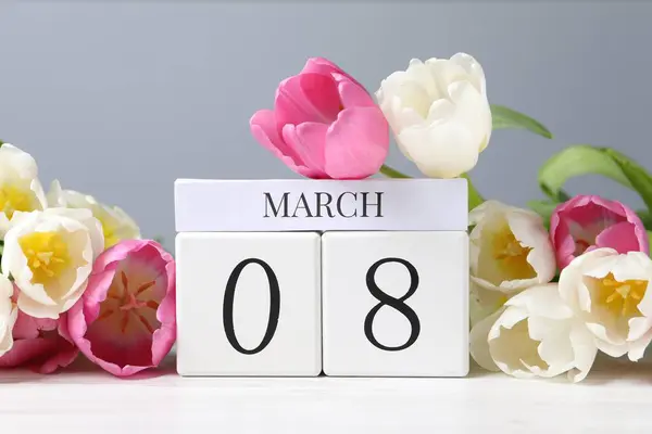 International Women\'s day - 8th of March. Wooden block calendar and beautiful flowers on white table