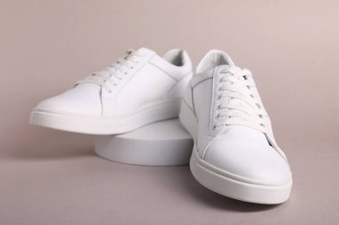 Gri arka planda bir çift şık beyaz spor ayakkabı.