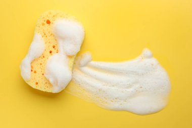Sarı arka planda köpüklü sünger, üst manzara. Metin için boşluk