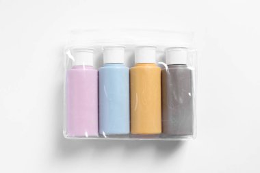 Beyaz arka planda plastik poşet içinde kozmetik seyahat kiti, üst görünüm