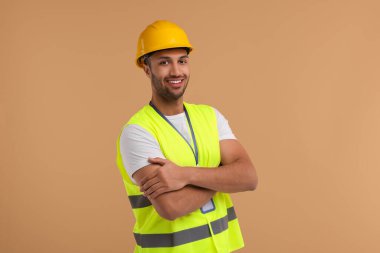 Bej arka planda kasketi ve rozeti olan mühendis.