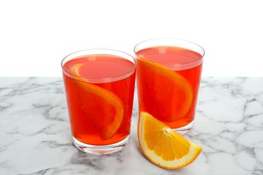 Aperol sprey kokteyli ve portakal dilimleri mermer masada beyaz arka planda.