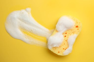 Sarı arka planda köpüklü sünger, üst manzara. Metin için boşluk