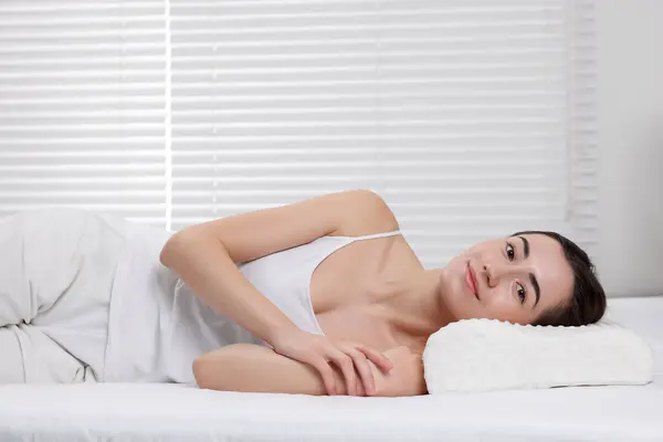 Woman lying on orthopedic pillow at home