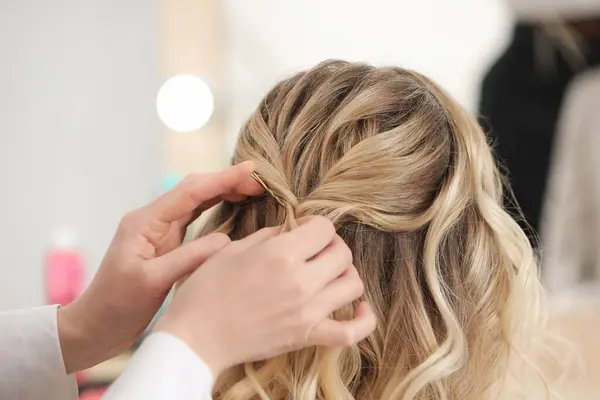 Hair styling. Professional hairdresser working with client in salon, closeup