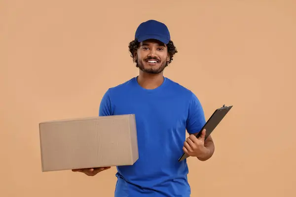 Happy courier with parcel and clipboard on light brown background