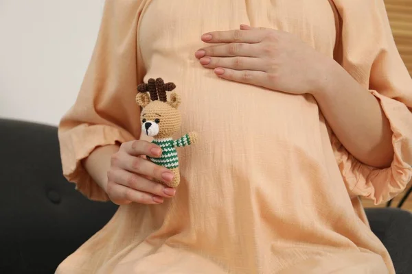 Pregnant woman with toy deer indoors, closeup