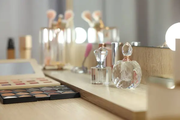 Cosmetic products and perfumes on wooden dressing table in makeup room