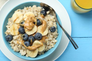 Muzlu, yabanmersinli ve fıstık ezmeli lezzetli yulaf ezmesi açık mavi ahşap masada servis edilir.