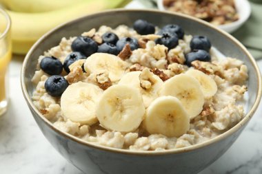 Muzlu yulaf ezmesi, yaban mersini, ceviz ve süt beyaz mermer masada servis edilir.