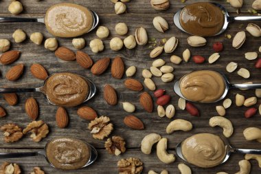 Kaşık içinde lezzetli fındık ezmesi ve ahşap masada çiğ fındık.