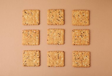 Bej arka planda keten ve susam tohumlu gevrek krakerleri, üst görünüm