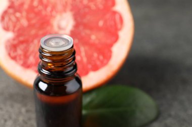 Şişede greyfurt yağı ve karanlık masada meyve, yakın plan. Metin için boşluk