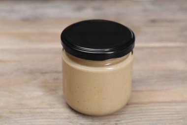 Kavanozdaki lezzetli fındık ezmesi ahşap masada, yakın plan.