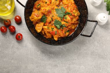 Lezzetli körili tavuk kızartma tavası, domates ve yağlı açık gri masa, düz yatak. Metin için boşluk