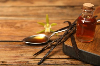 Aromatik vanilya özü, kapsüller ve çiçek ahşap masada. Metin için boşluk