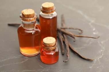 Siyah masanın üzerinde Aromatik vanilya özü ve kapsüller, yakın plan.