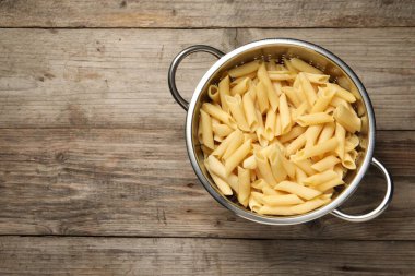 Ahşap masadaki süzgeçli makarna nefis görünüyor. Metin için boşluk