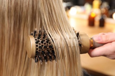 Kuaför kuaförde müşterinin saçını tarıyor.