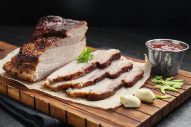 Kurutulmuş domuz eti parçaları soslu ve maydanozlu siyah desenli masa, yakın plan.