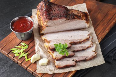 Kurutulmuş domuz eti parçaları soslu ve maydanozlu siyah desenli masa, yakın plan.