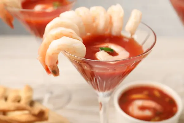 Tasty shrimp cocktail with sauce in glass on table, closeup