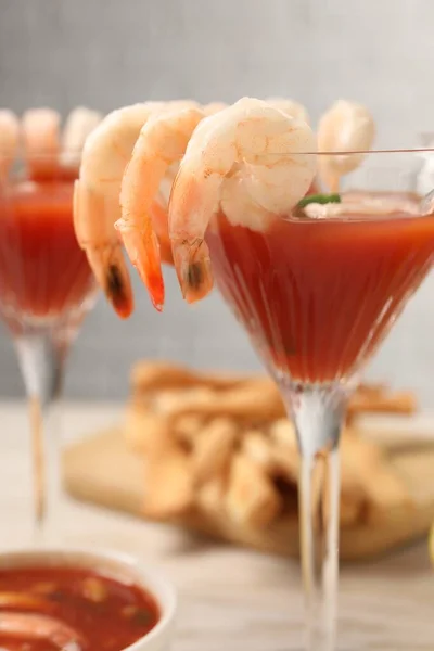 Tasty shrimp cocktail with sauce in glasses on light wooden table, closeup