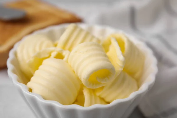 Tasty butter curls in bowl on table, closeup