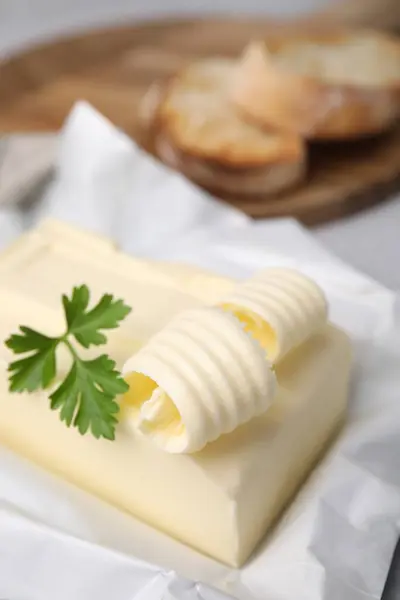 Tasty butter with curl and parsley on table, closeup