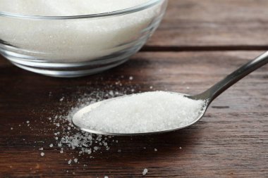 Kase içinde granüle şeker ve tahta masada kaşık, yakın plan.